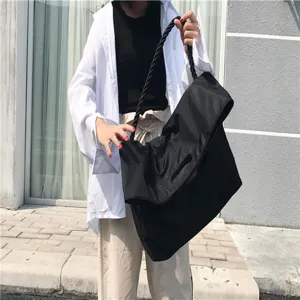 Λεπτομέρεια μαύρης νάιλον τσάντας με πτυσσόμενο πτερύγιο, λαβή από σχοινί και μεγάλη χωρητικότητα.