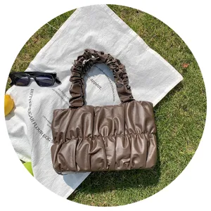 Detail view of stylish dark brown ruched cloud handbag, soft leather crossbody design.