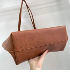 Detailed view of brown pebbled leather tote bag showing soft texture and bottom structure.