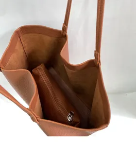 Detailed view of the brown leather tote bag interior showing the matching zipper pouch inside.
