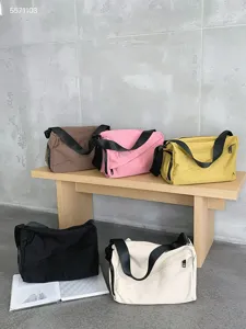 Detail shot of versatile casual oxford cloth crossbody bags in multiple colors on a wooden bench.