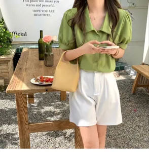Detail view of a stylish yellow bucket bag held by a model in a cafe setting, soft material.