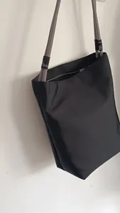 Borsa a spalla in nylon nero con manici in corda grigia e chiusura a zip per uso quotidiano.