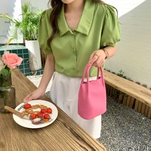 Detailed shot of trendy pink leather bucket bag in cozy lifestyle cafe setting now.