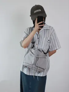Dettaglio borsa a secchiello in nylon grigio con spallacci regolabili e chiusura a cordoncino.