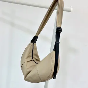 Beige nylon crescent shoulder bag, casual minimalist dumpling bag for daily use and travel.