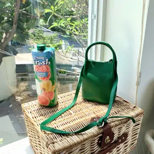 Green textured leather bucket bag with top handle and crossbody strap, stylish.