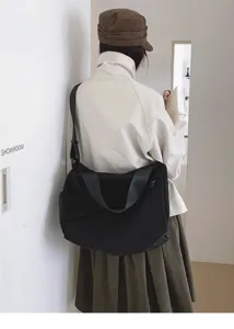 Detail view of the minimalist black oxford cloth shoulder bag, showing large capacity and strap.
