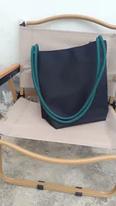 Vista dettagliata di una borsa casual in nylon nero con spessi manici in corda verde per uso.