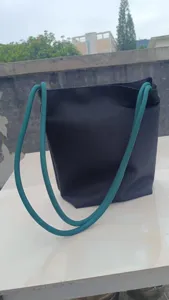 Vista dettagliata della borsa a secchiello nera con manici in corda verde casual.