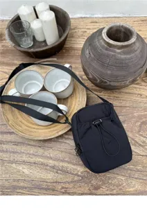 Detailed view of a minimalist black nylon mini crossbody bag with drawstring closure.