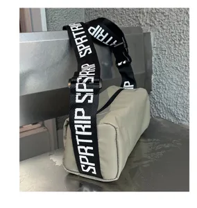 Detailed view of the cylindrical casual shoulder bag with wide printed letter strap.