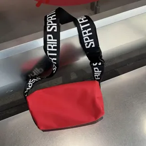 Red waterproof cylinder crossbody bag, stylish wide letter strap shoulder bag for women.