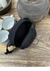Minimalist black nylon crossbody phone bag for casual daily use with zipper and strap.