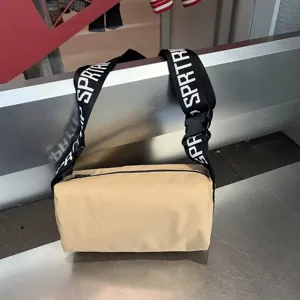 Detailed view of beige waterproof crossbody bag with wide black strap and zipper closure.