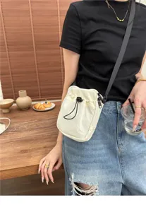 Japanese minimalist nylon crossbody phone bag detail shot, showing drawstring closure and strap.