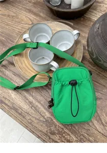 Detailed view of the green nylon crossbody phone bag with drawstring pocket and strap.