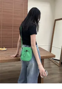 Detailed view of a casual green nylon crossbody bag worn by a model in a natural indoor setting.