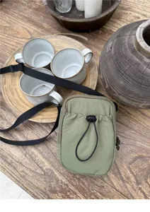 Detailed shot of green nylon crossbody phone bag with drawstring, casual minimalist style.