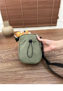 Green nylon crossbody phone bag detail view, casual lightweight mini shoulder pouch with drawstring.