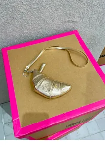 Metallic gold croissant shaped mini crossbody bag coin purse with strap, stylish unique accessory.