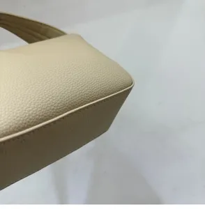 Detailed shot of the minimalist beige pebbled leather handbag showing fine texture and stitching.