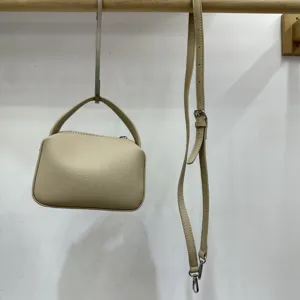 Minimalist solid color leather handbag and crossbody lunch box bag with detachable strap.