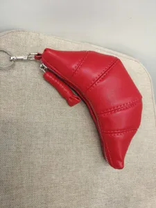 Red leather croissant coin purse detail showcasing soft texture and metal zipper hardware.