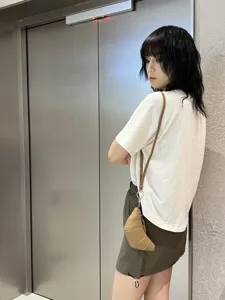 Detailed view of the soft leather croissant crossbody bag worn by a model in an elevator.