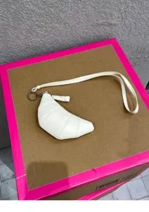 White leather croissant coin purse detail shot with lanyard and ring attachment.