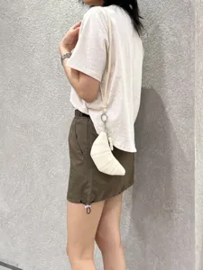 Detailed shot of mini white soft leather croissant bag hanging on body, vintage style.