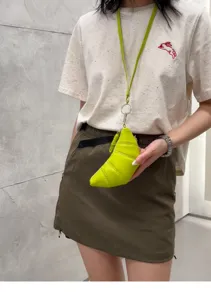 Detail shot of a niche design soft leather neon yellow croissant coin purse with long lanyard.