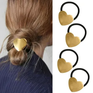 Gold metal heart hair tie detail view showing ponytail holder accessory design and texture.
