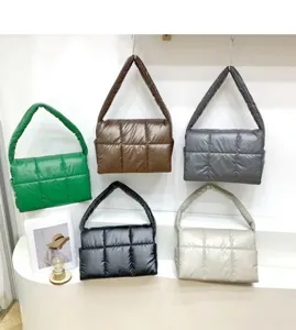 Close-up detail shot of various colored quilted puffer underarm bags displayed on a white shelf.