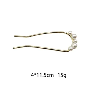 Gold U-shaped hair fork detail, metal hair pin with white pearl decoration, accessory closeup.