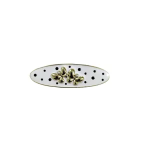 Detailed view of gold butterfly hair clip with white enamel polka dots and pearl accents.