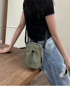 Casual green nylon crossbody bag detail, featuring adjustable strap and front pocket.