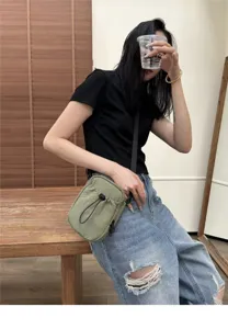Close-up detail of the lightweight nylon crossbody phone bag in casual style, worn on model.