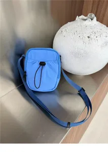 Detailed view of a casual blue nylon crossbody phone bag with drawstring closure and strap.