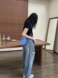Detailed view of the casual nylon crossbody phone bag worn by a model in indoor scene.