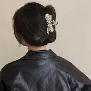 Close-up detail shot of a stylish gold hair claw clip adorned with sparkling rhinestones and pearls.
