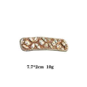 Close-up of sparkling rhinestone hair clip detail, showcasing crystal settings and curved shape.