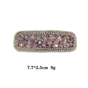 Detailed close-up of sparkling crystal hair clip, pink rhinestone barrette details.
