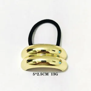 Nahaufnahme des minimalistischen goldenen Metalldutt-Haargummis mit geometrischem Bogen.