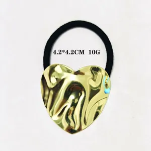 Nahaufnahme des minimalistischen unregelmässigen goldenen Herz-Haargummis mit schwarzem Band.