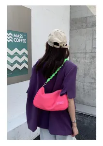 Stylish pink canvas underarm bag with bright green braided strap, perfect daily commute chic.
