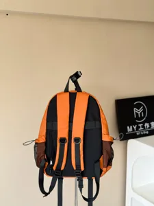 Vue détail du sac à dos avec tissu orange noir, poches multiples et filet latéral.