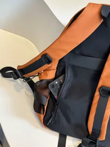 Gros plan détaillé de la sangle de sac à dos orange et noir et de la poche latérale.