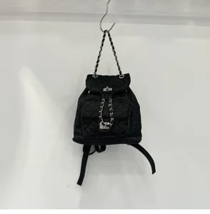 Black denim quilted mini backpack with woven chain straps and turn-lock closure for daily wear.