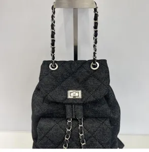 Black denim quilted backpack with chain straps and turn lock closure for daily fashion wear.